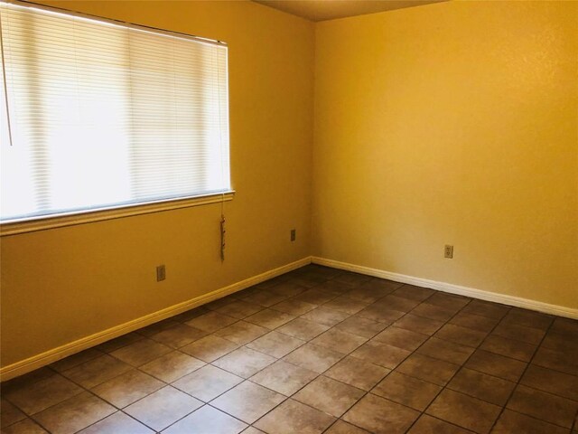 unfurnished room featuring a wealth of natural light, tile patterned flooring, and baseboards