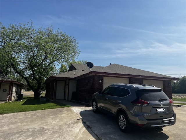 view of front of house with an attached garage, driveway, and roof with shingles