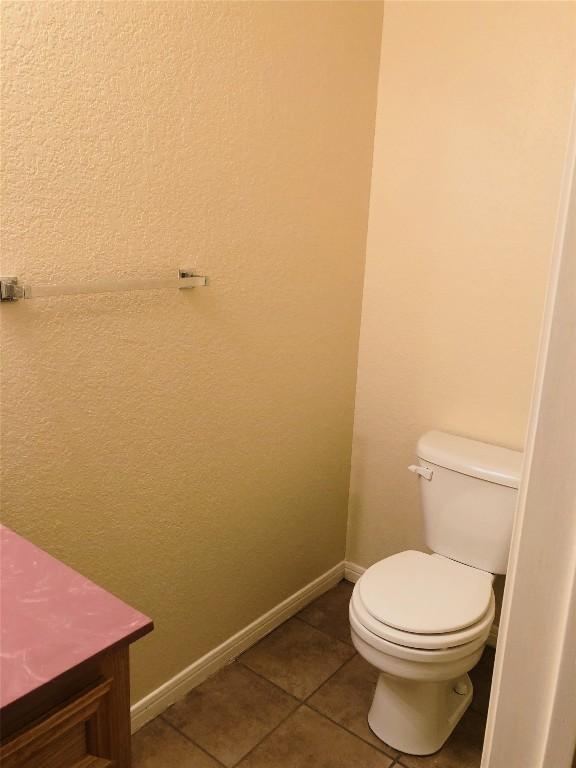 bathroom with tile patterned floors, baseboards, and toilet