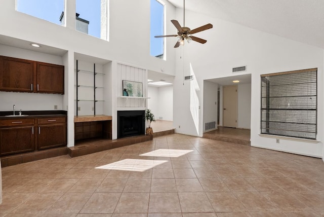 unfurnished living room featuring high vaulted ceiling, a sink, built in features, a ceiling fan, and light tile patterned floors
