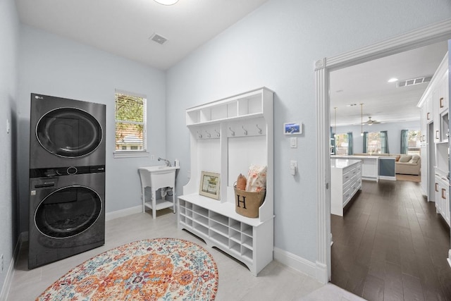 laundry room with stacked washer and clothes dryer and baseboards