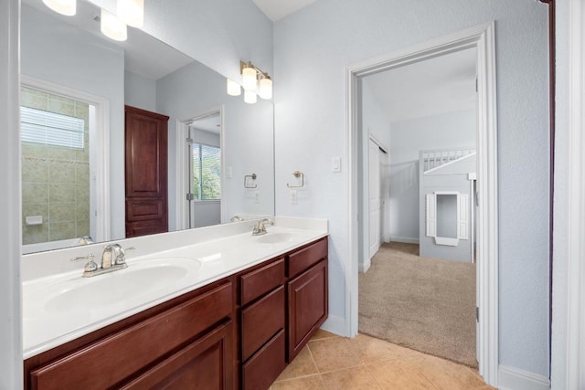 full bath with double vanity, tile patterned floors, and baseboards