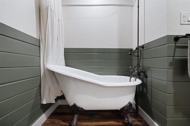 67 Augusta Dr, Wimberley, TX 78676 - bathroom featuring wood finished floors, a freestanding tub, and a wainscoted wall