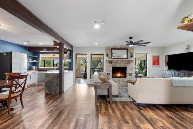 67 Augusta Dr, Wimberley, TX 78676 - living area with a stone fireplace, dark wood-style flooring, ceiling fan, recessed lighting, and beam ceiling