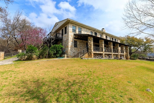 rear view of property featuring a yard, stone siding, and a chimney