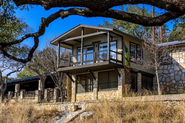 view of front of house with stone siding and a balcony