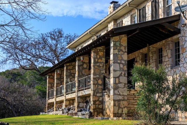 view of side of property with a lawn, a sunroom, and stone siding