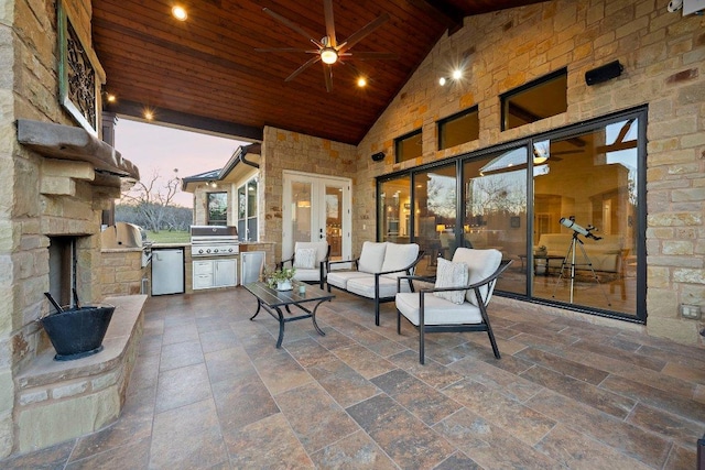 patio terrace at dusk with an outdoor kitchen, ceiling fan, an outdoor hangout area, and a grill