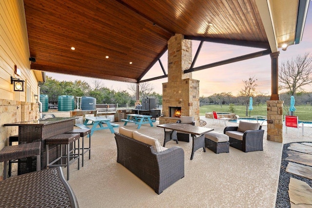 view of patio / terrace featuring an outdoor living space with a fireplace, an outdoor bar, and exterior kitchen
