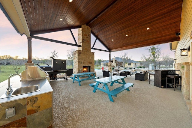 view of patio / terrace with an outdoor living space with a fireplace, a sink, and area for grilling