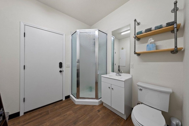 bathroom featuring toilet, vanity, wood finished floors, and a stall shower