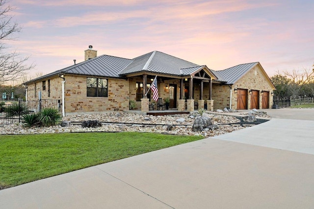 view of front of home featuring stone siding, a standing seam roof, driveway, and metal roof