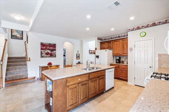 719 Walsh Hill Trl, Cedar Park, TX 78613 - kitchen featuring white appliances, a sink, arched walkways, brown cabinets, and a center island with sink