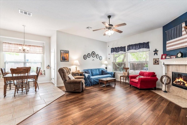 719 Walsh Hill Trl, Cedar Park, TX 78613 - living room with a chandelier, wood finished floors, a tiled fireplace, and a ceiling fan