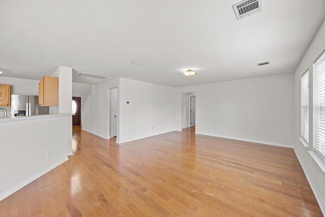 1444 Newbury St, Georgetown, TX 78626 - unfurnished living room featuring light wood-style flooring, plenty of natural light, baseboards, and a sink