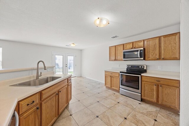 1444 Newbury St, Georgetown, TX 78626 - kitchen with stainless steel appliances, a sink, light countertops, french doors, and a textured ceiling