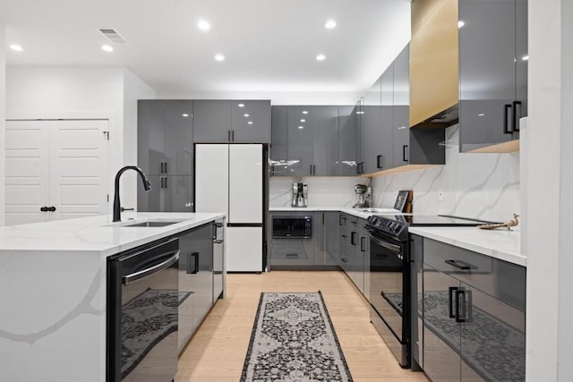 6002 Ponca St Unit 1, Austin, TX 78741 - kitchen with black appliances, gray cabinets, modern cabinets, an island with sink, and light wood-style flooring