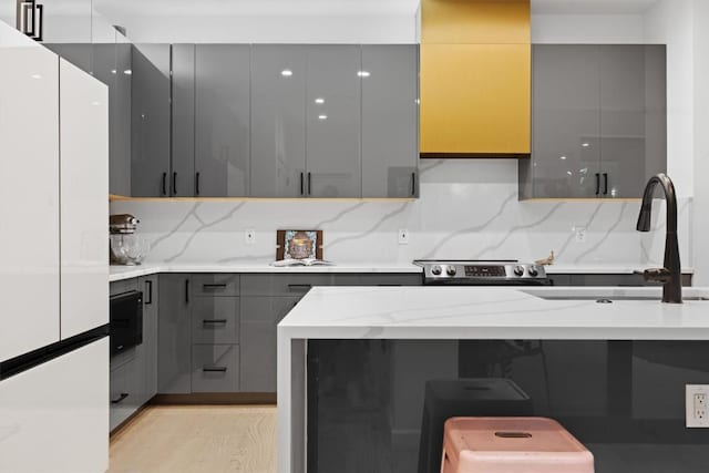 6002 Ponca St Unit 1, Austin, TX 78741 - kitchen with gray cabinets, freestanding refrigerator, modern cabinets, backsplash, and light stone counters