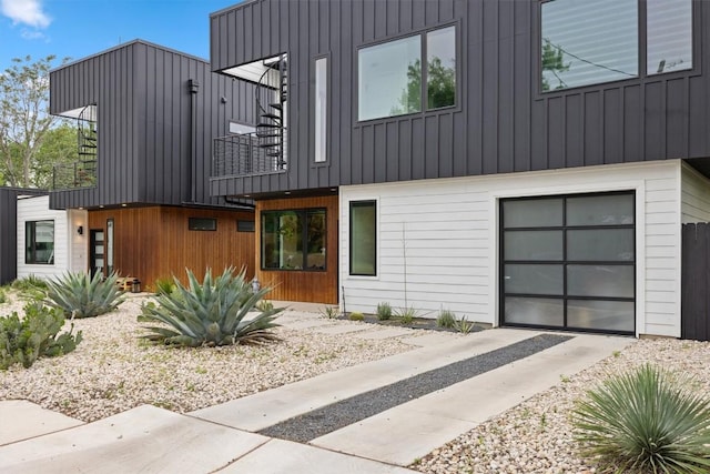 6002 Ponca St Unit 1, Austin, TX 78741 - view of front facade with a balcony, board and batten siding, concrete driveway, and an attached garage