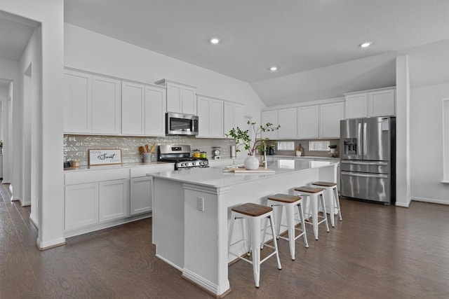600 Spurlock Way, Liberty Hill, TX 78642 - kitchen with stainless steel appliances, lofted ceiling, dark wood finished floors, backsplash, and a kitchen breakfast bar