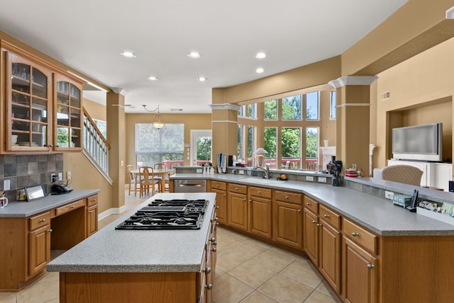 kitchen featuring light tile patterned flooring, glass insert cabinets, a kitchen island, and black gas stovetop