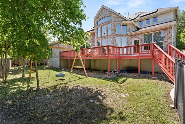 rear view of property with a yard, brick siding, fence, and a deck