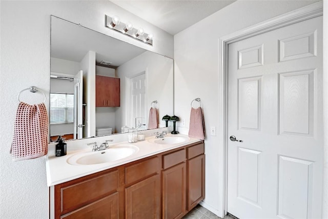 full bathroom featuring toilet, visible vents, a sink, and double vanity