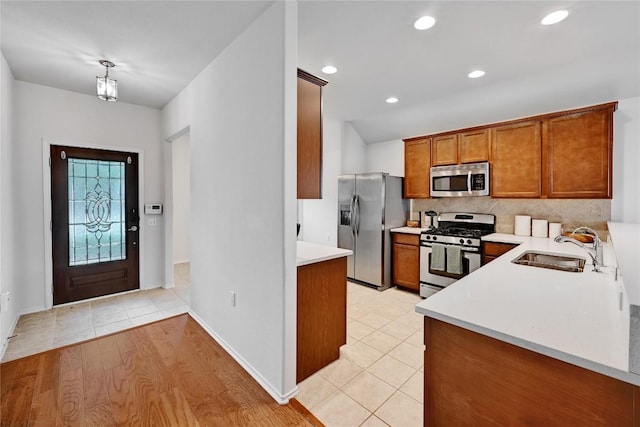 kitchen with brown cabinets, appliances with stainless steel finishes, a sink, and light countertops