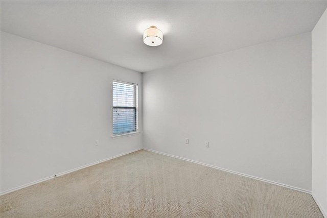 spare room with baseboards and light carpet