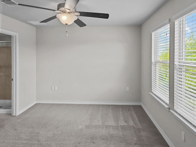 carpeted empty room with baseboards, a ceiling fan, and visible vents