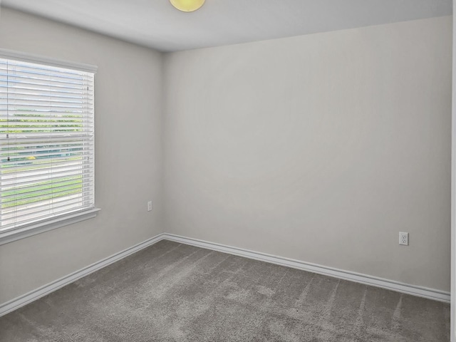 empty room with dark carpet and baseboards