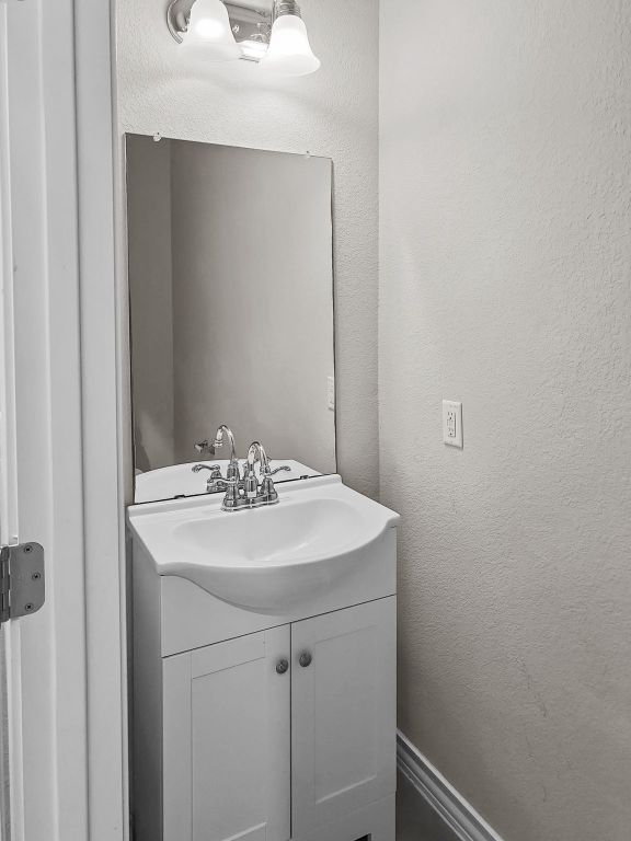 bathroom with a textured wall and vanity