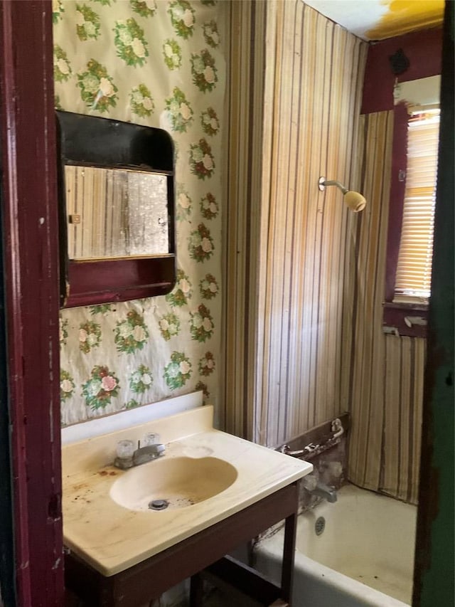 full bathroom with a sink and wallpapered walls