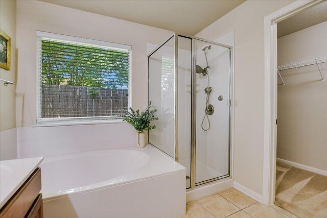18301 Masi Loop, Pflugerville, TX 78660 - full bathroom featuring a shower stall, a garden tub, a walk in closet, vanity, and tile patterned floors
