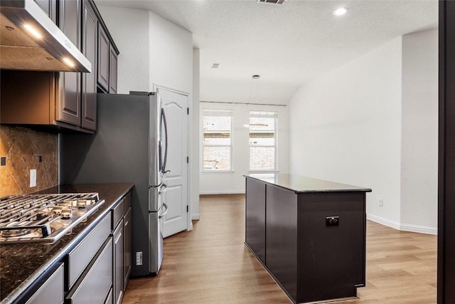 kitchen with appliances with stainless steel finishes, light wood-style floors, extractor fan, and a center island