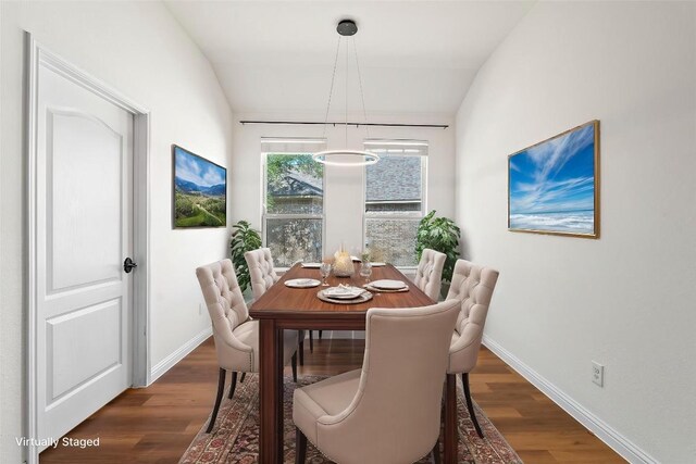 dining space featuring lofted ceiling, dark wood-type flooring, and baseboards