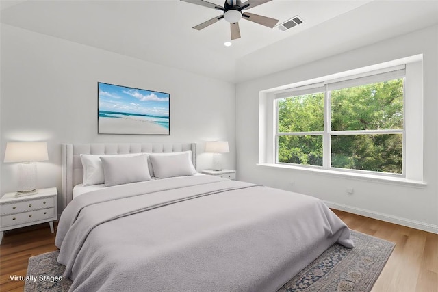 bedroom with lofted ceiling, visible vents, baseboards, wood finished floors, and a ceiling fan