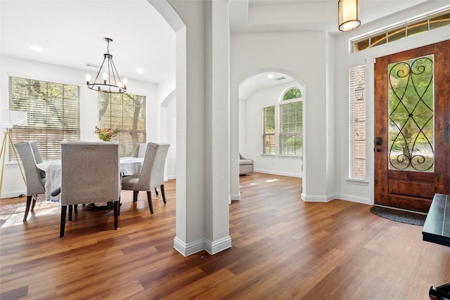 foyer entrance with recessed lighting, arched walkways, wood finished floors, a chandelier, and baseboards