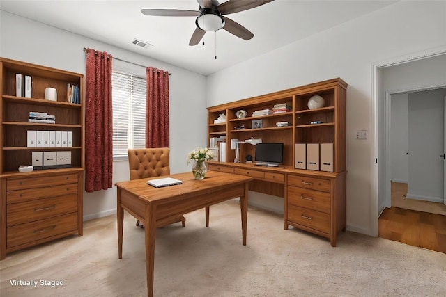 home office featuring visible vents, ceiling fan, light colored carpet, and baseboards