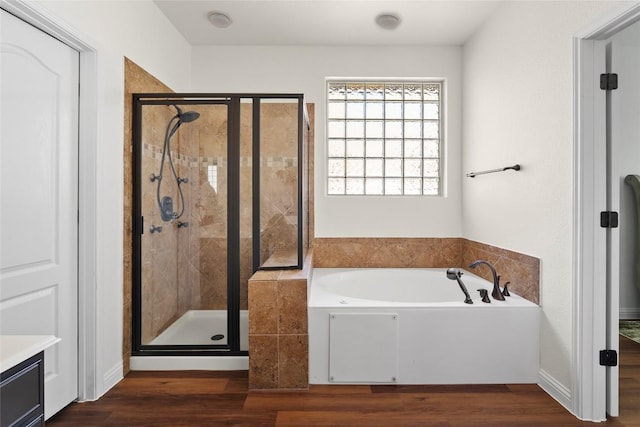 full bathroom with a stall shower, a bath, wood finished floors, and vanity