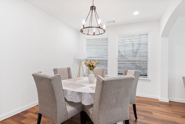 dining area featuring arched walkways, visible vents, a chandelier, and baseboards