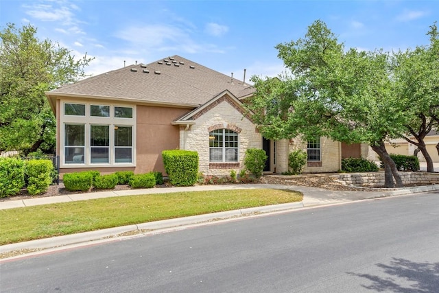 109 Perpetuation Dr, Austin, TX 78734 - view of front of house featuring stone siding, a shingled roof, stucco siding, and a front yard