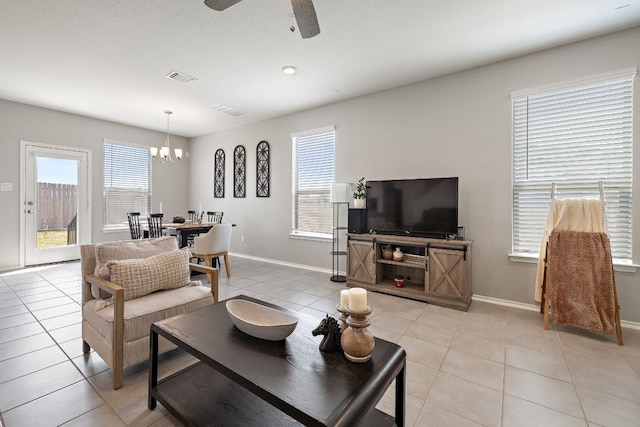 living area with baseboards, ceiling fan with notable chandelier, visible vents, and light tile patterned floors