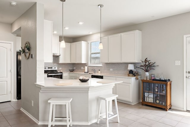 kitchen featuring light tile patterned floors, a peninsula, a breakfast bar, and stainless steel range with electric stovetop