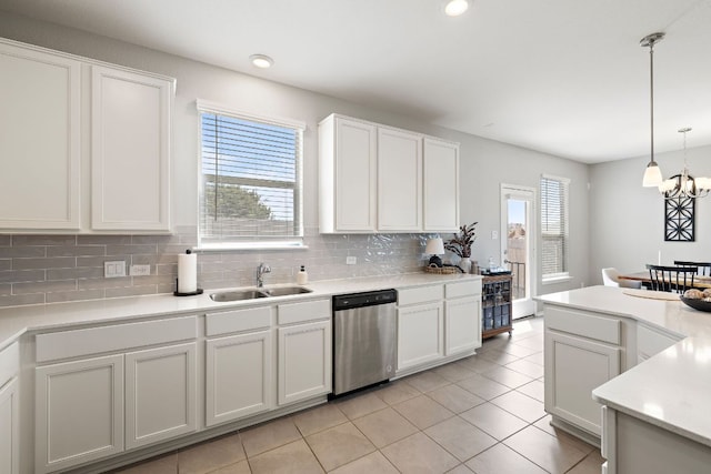 kitchen featuring stainless steel dishwasher, a sink, light countertops, backsplash, and white cabinetry
