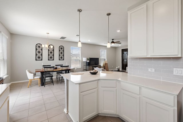 kitchen featuring white cabinets, a peninsula, backsplash, light countertops, and light tile patterned floors