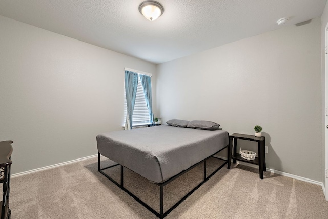 bedroom featuring light carpet, a textured ceiling, and baseboards
