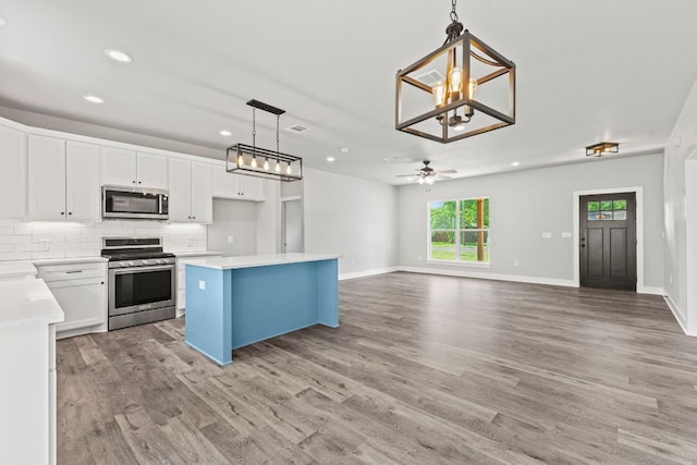 kitchen featuring white cabinets, decorative backsplash, stainless steel appliances, and light wood finished floors