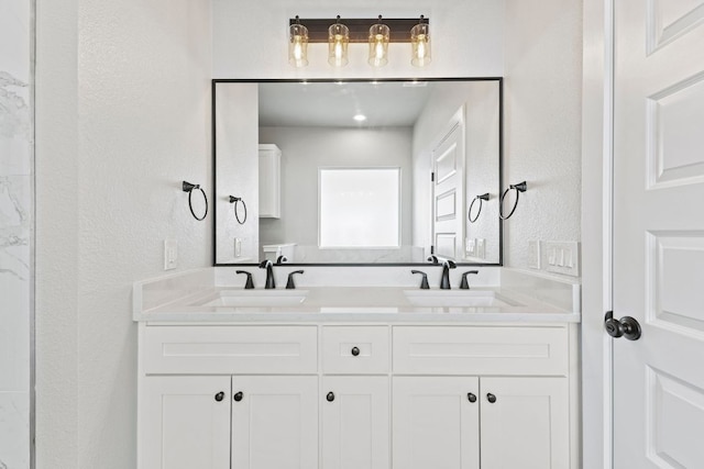 bathroom featuring double vanity, a textured wall, and a sink
