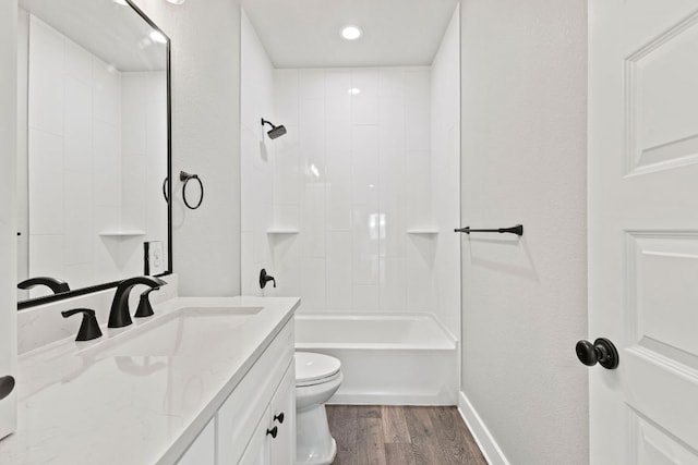 bathroom with wood finished floors, toilet, vanity, baseboards, and  shower combination